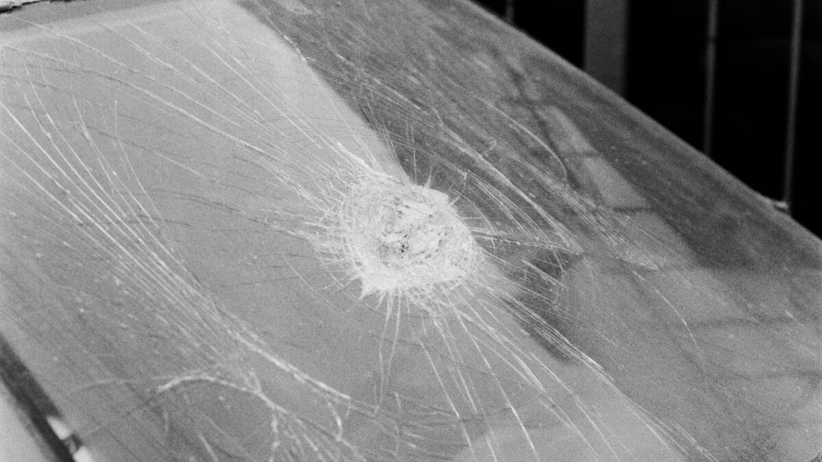 A monochrome image of a car with a broken windshield, emphasizing damage and texture.